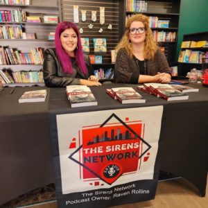 Alecia Lockhart (left) and LaDonna Humphrey (right) sit behind a table with copies of the book they wrote together, Strangled